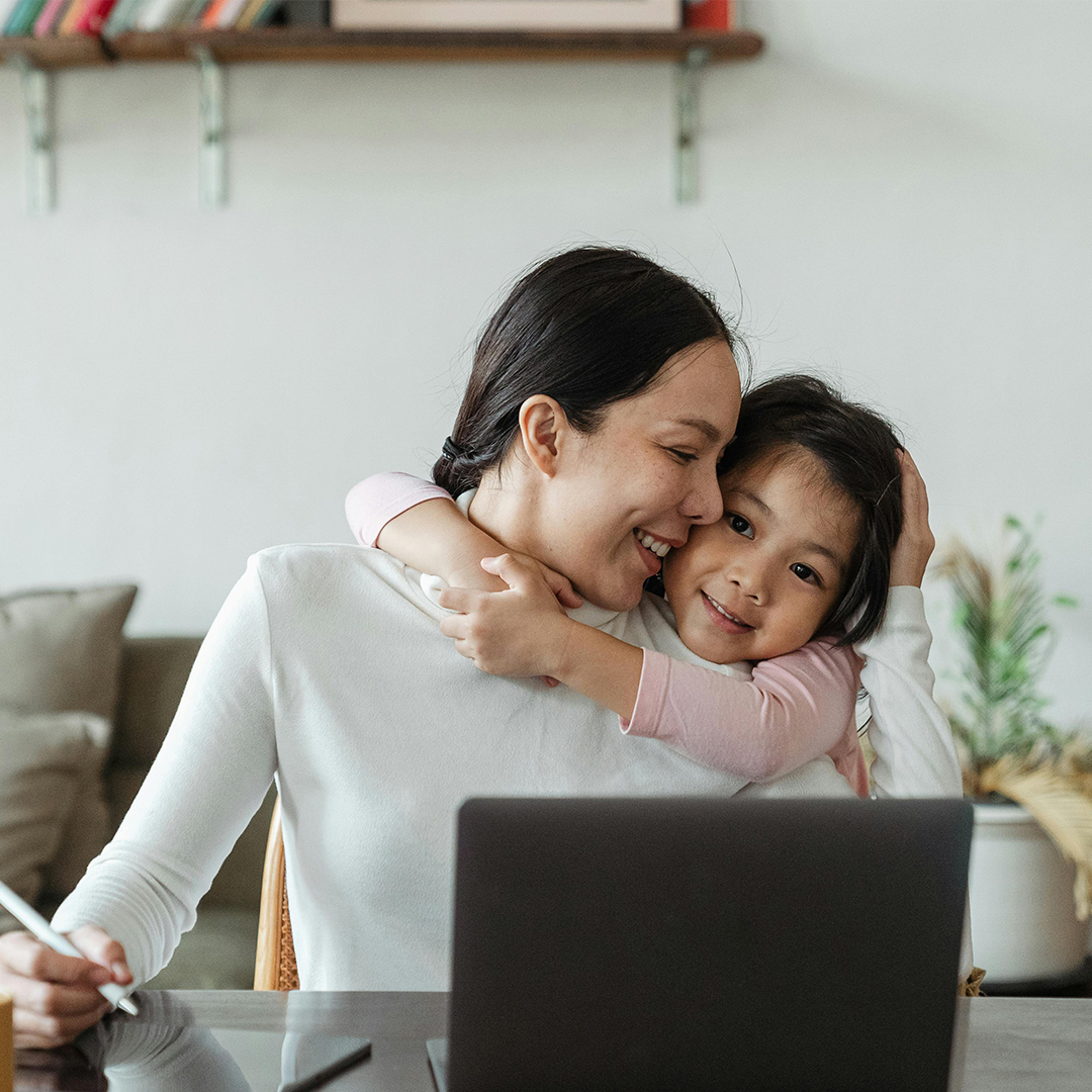 mom working from home with child on her shoulder smiling