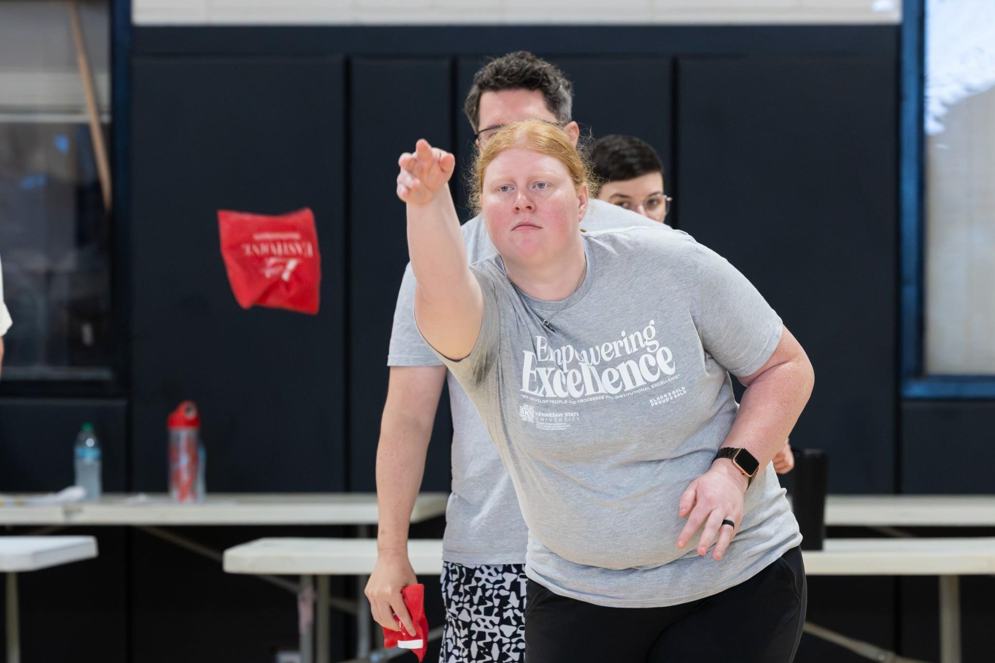 2026 Owlympics / focused woman tossing beanbag during game.