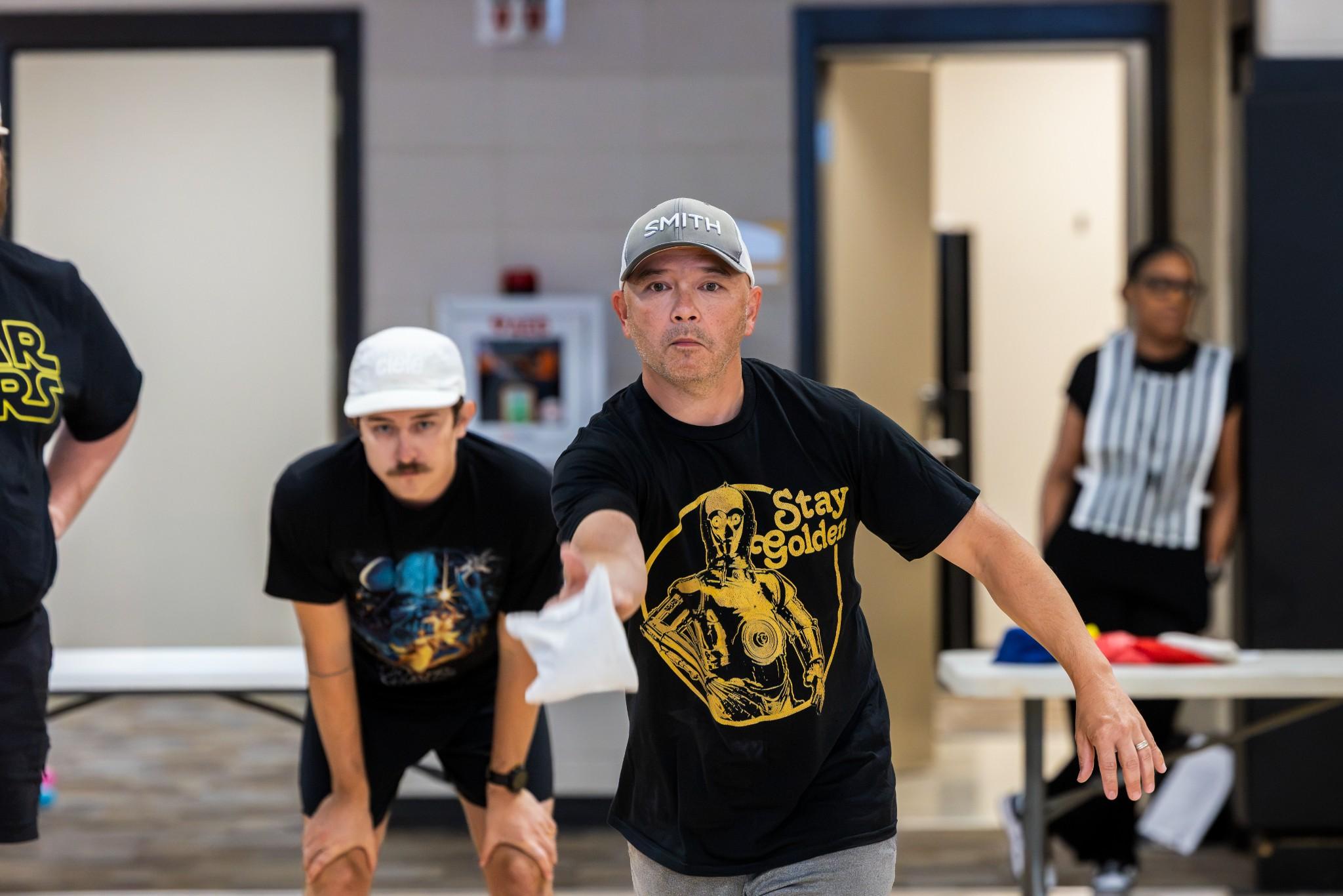 2026 Owlympics / Owlympics participant tossing a bean bag during one of the games while team members look on