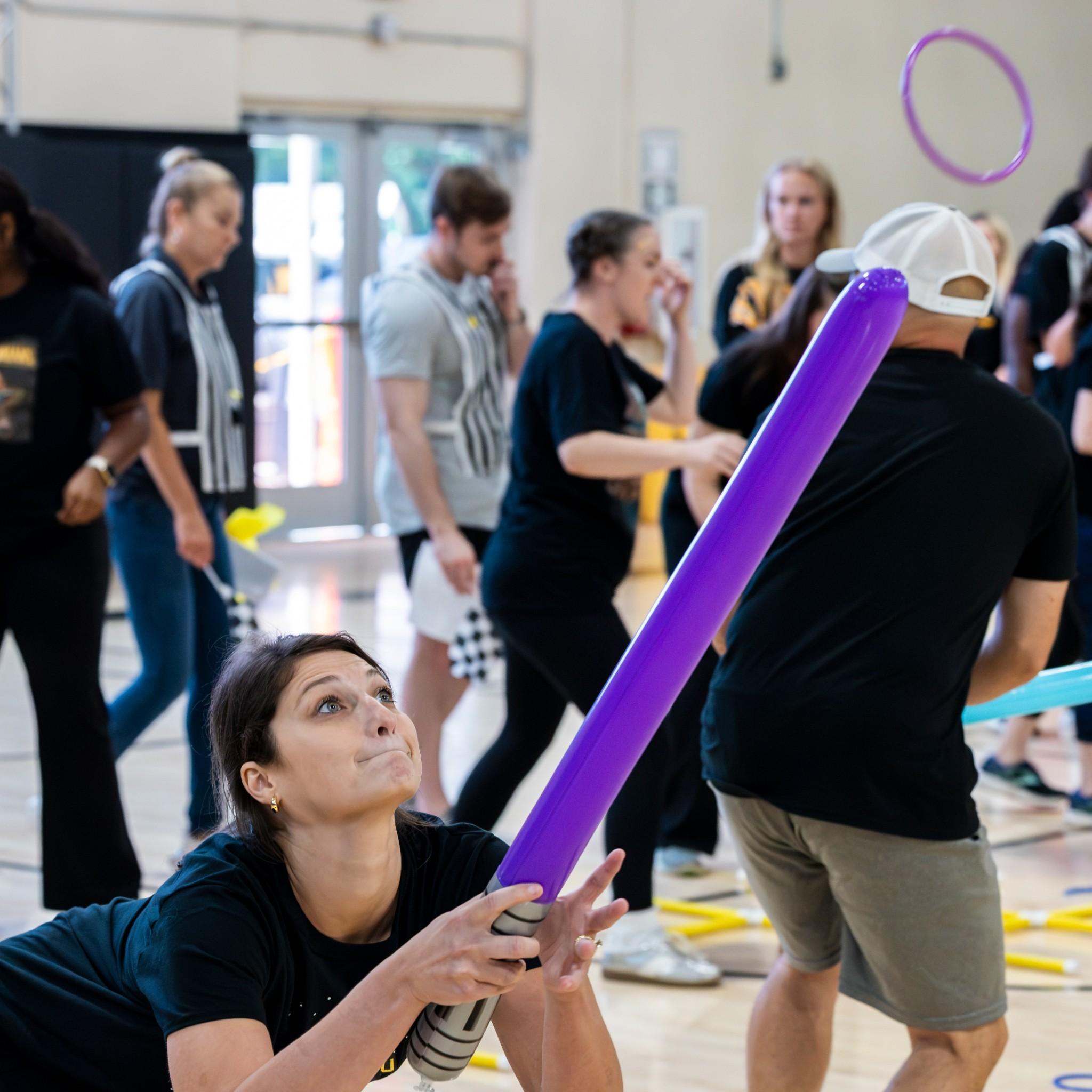  / Woman tries to catch ring on a purple light saber during Owlympics event