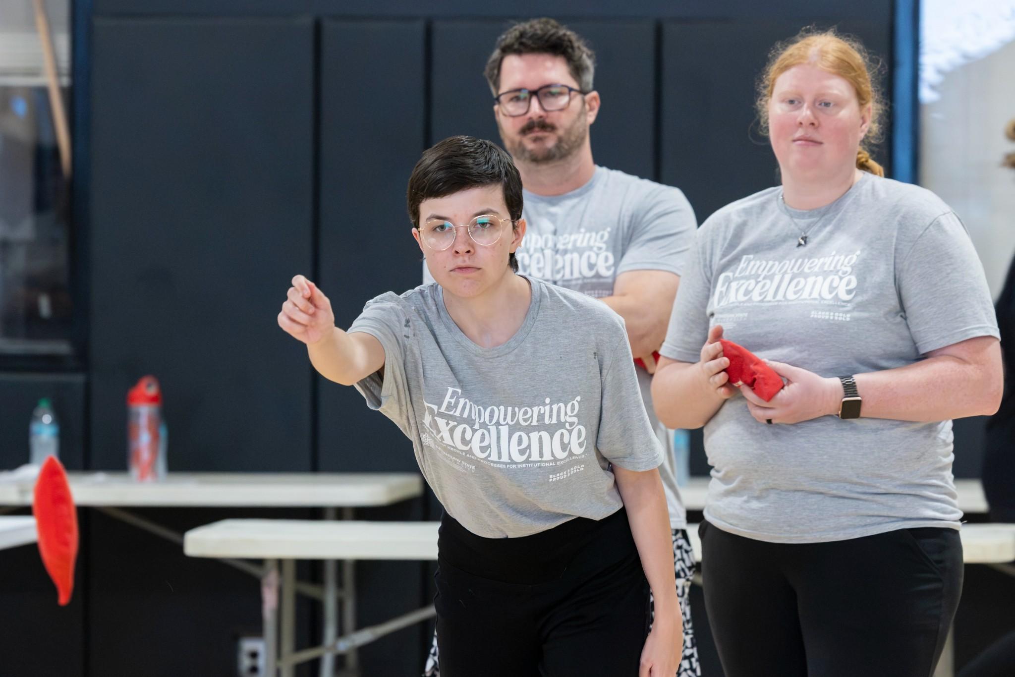 2026 Owlympics / Owlympics competitor tossing a bean bag during the games while teammates watch.