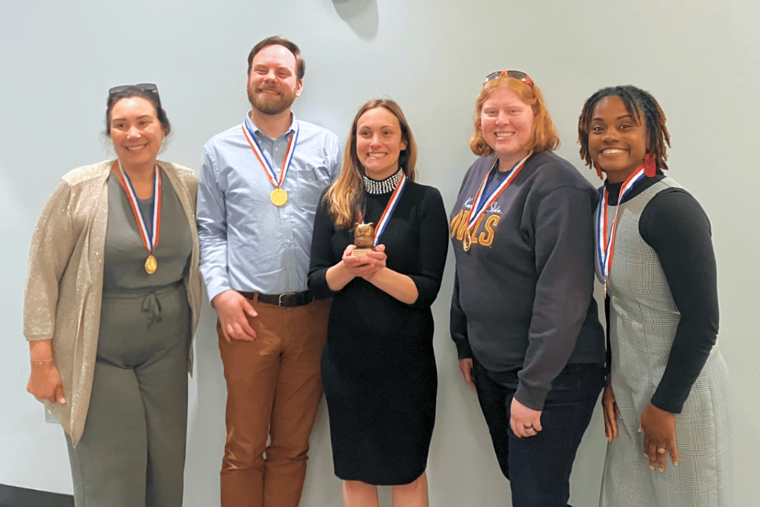 first place Trivia winners wearing medals, smiling and showing off their owl trophy..