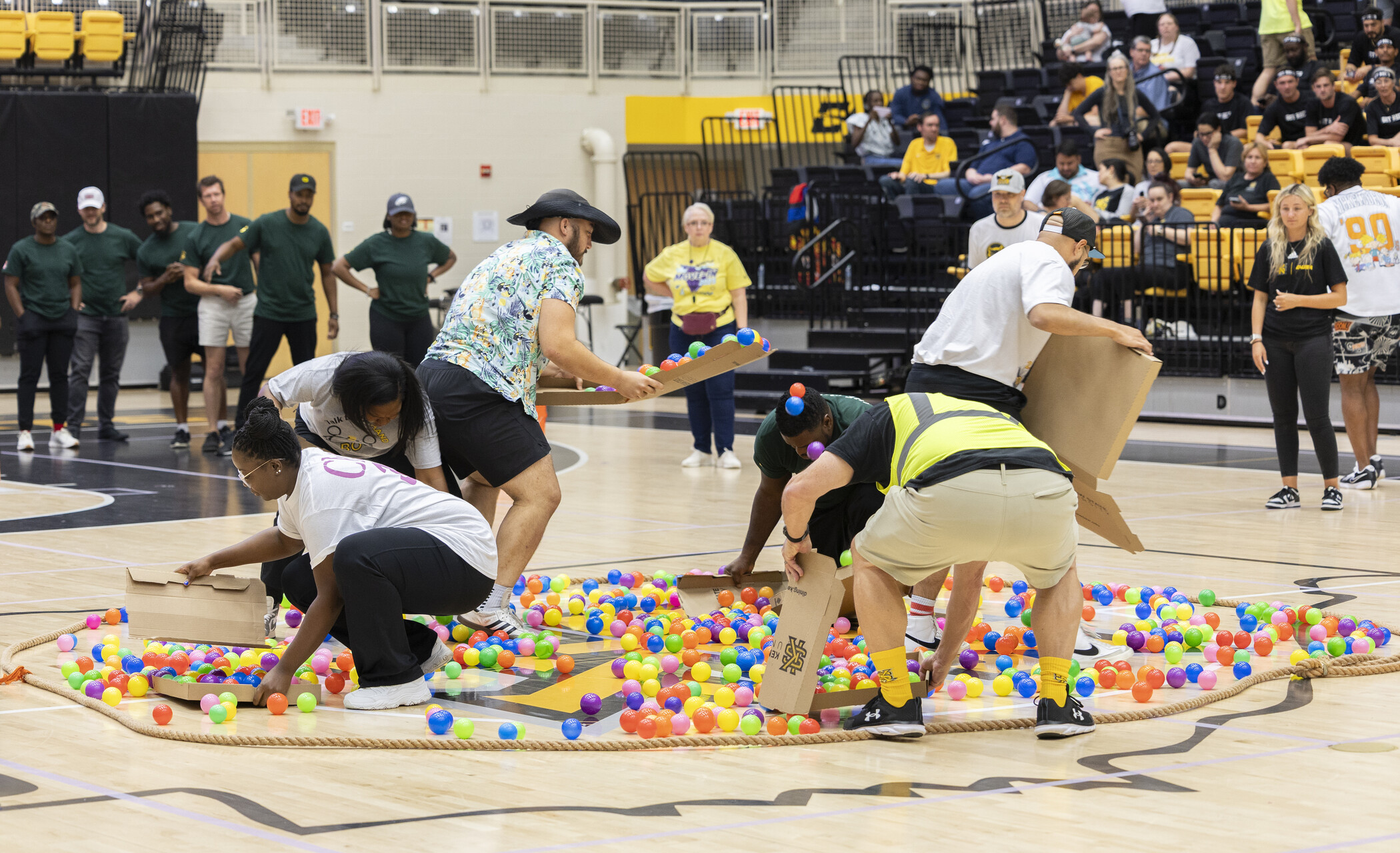 ksu employees racing to gathering balls that are scattered along the gynamsium floor in an effort to grab the most