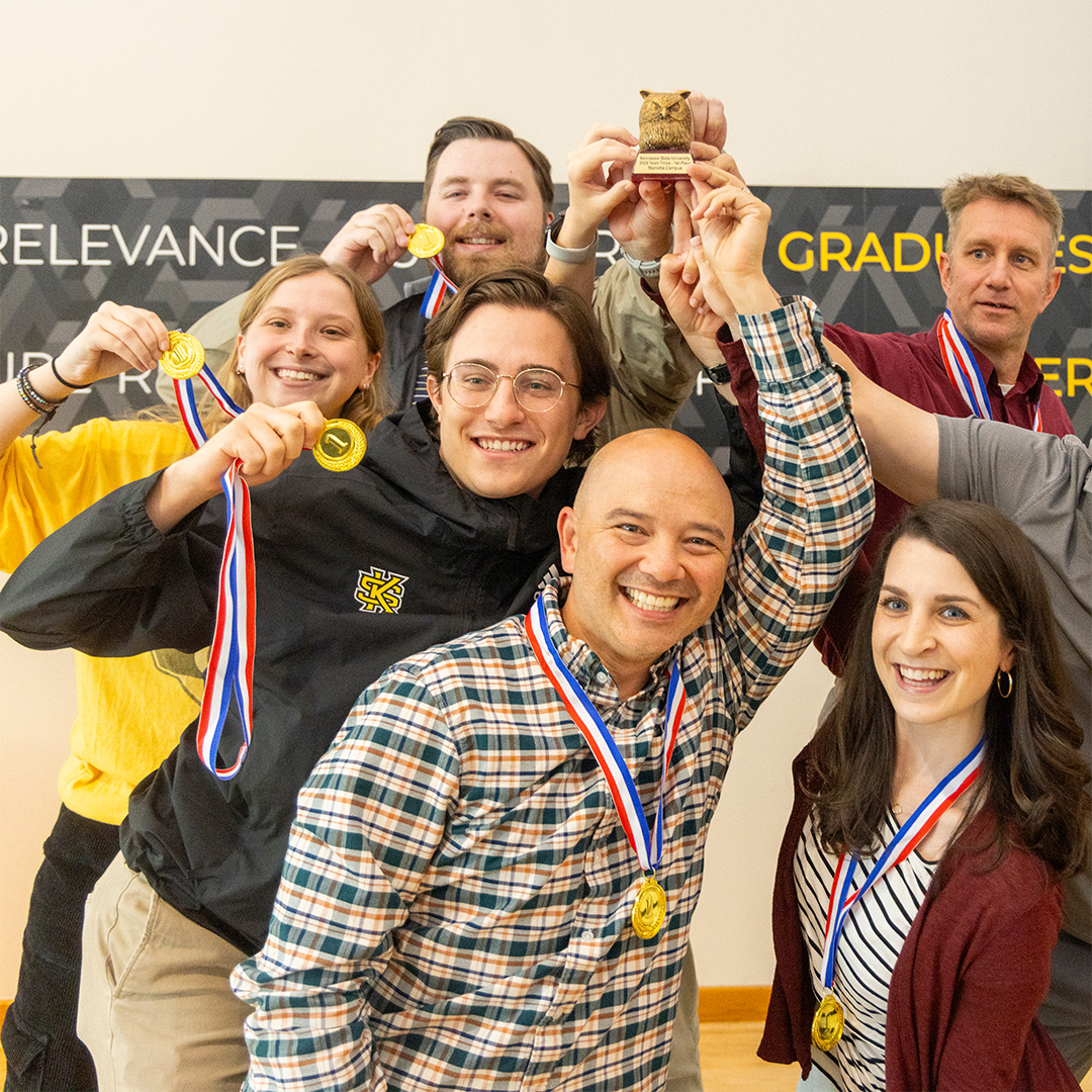 ksu faculty holding up awards during trivia event