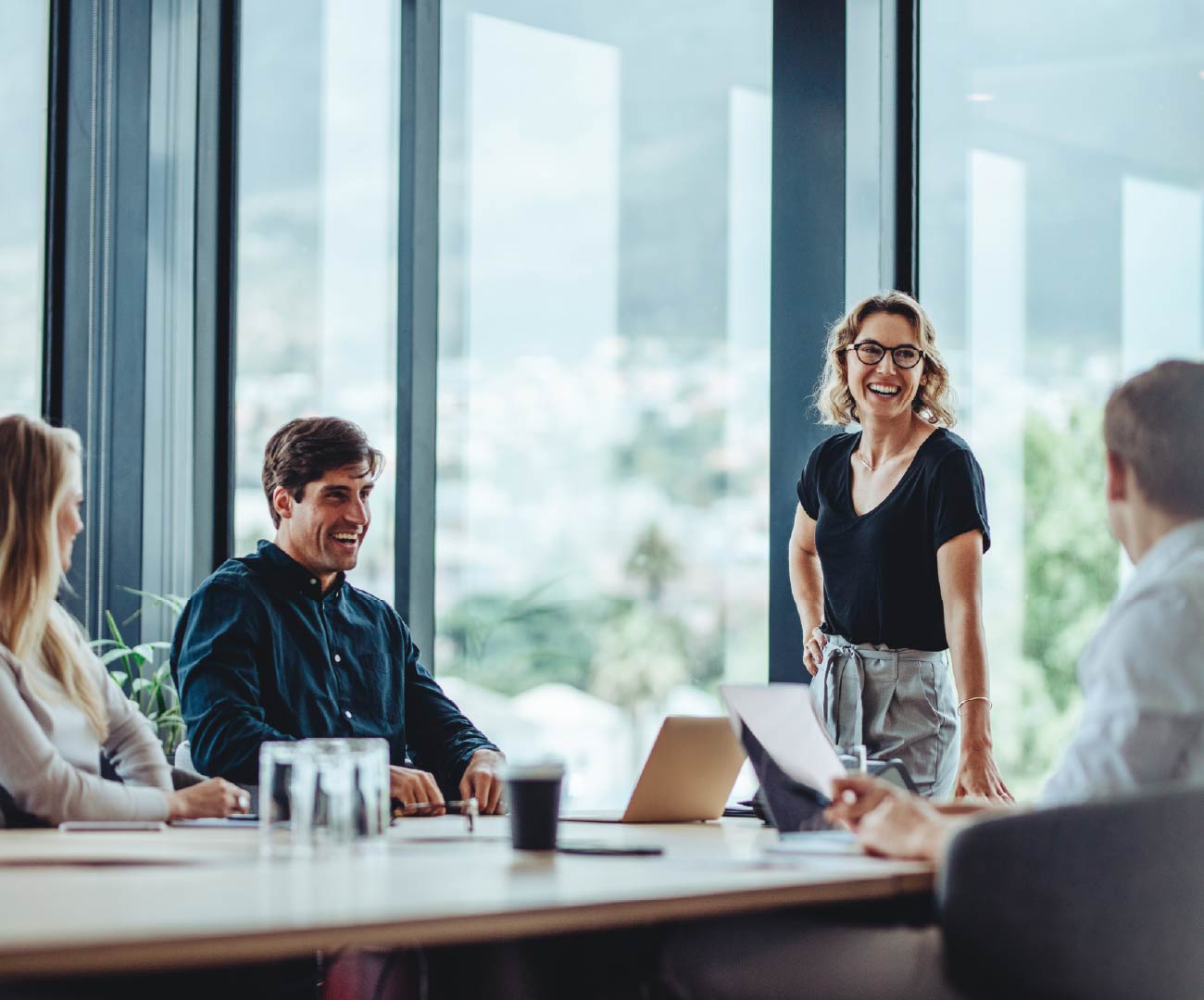 group of diverse leaders listening to and smiling at their female leader