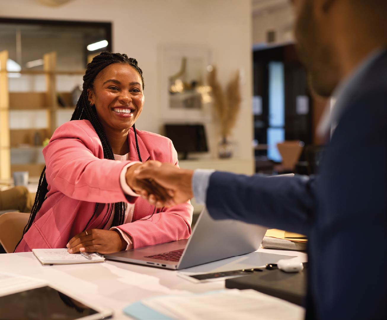 female in office setting smiling and shaking hands