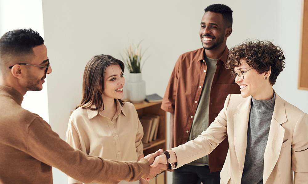 group of diverse friends in office setting smiling and shaking hands