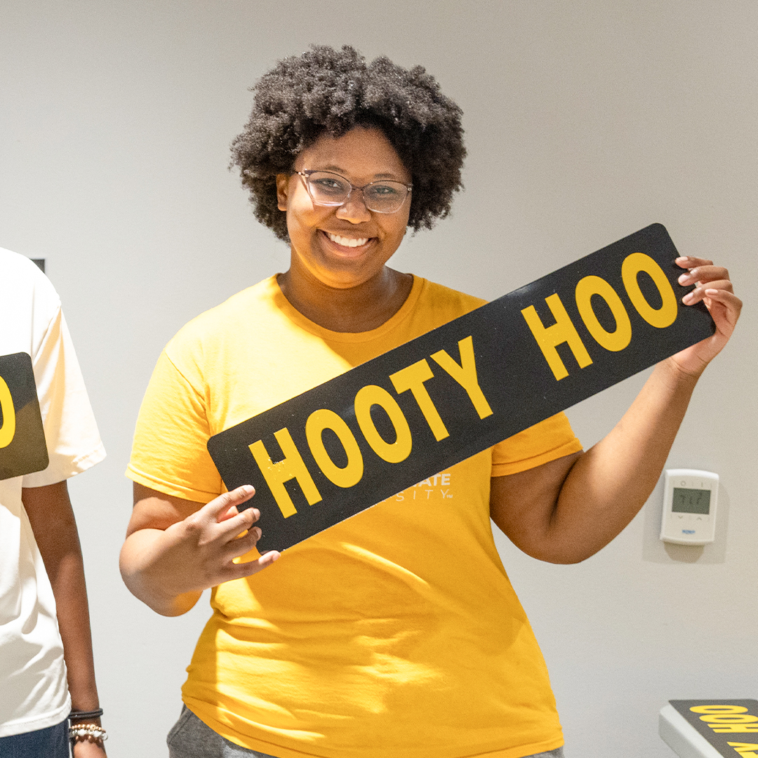 ksu member smiling holding up hooty hoo sign