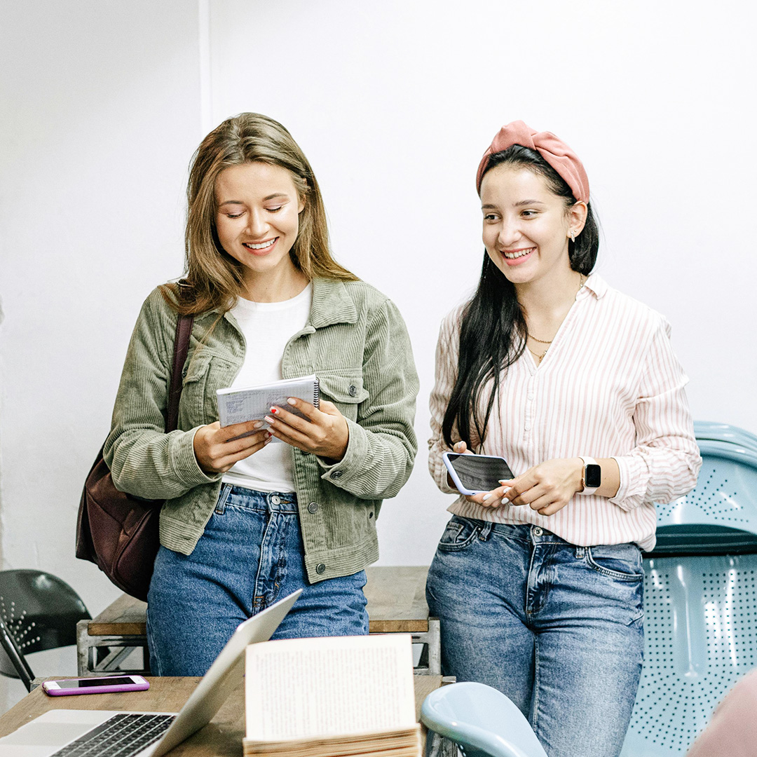 two females smiling standing next to eachother in office