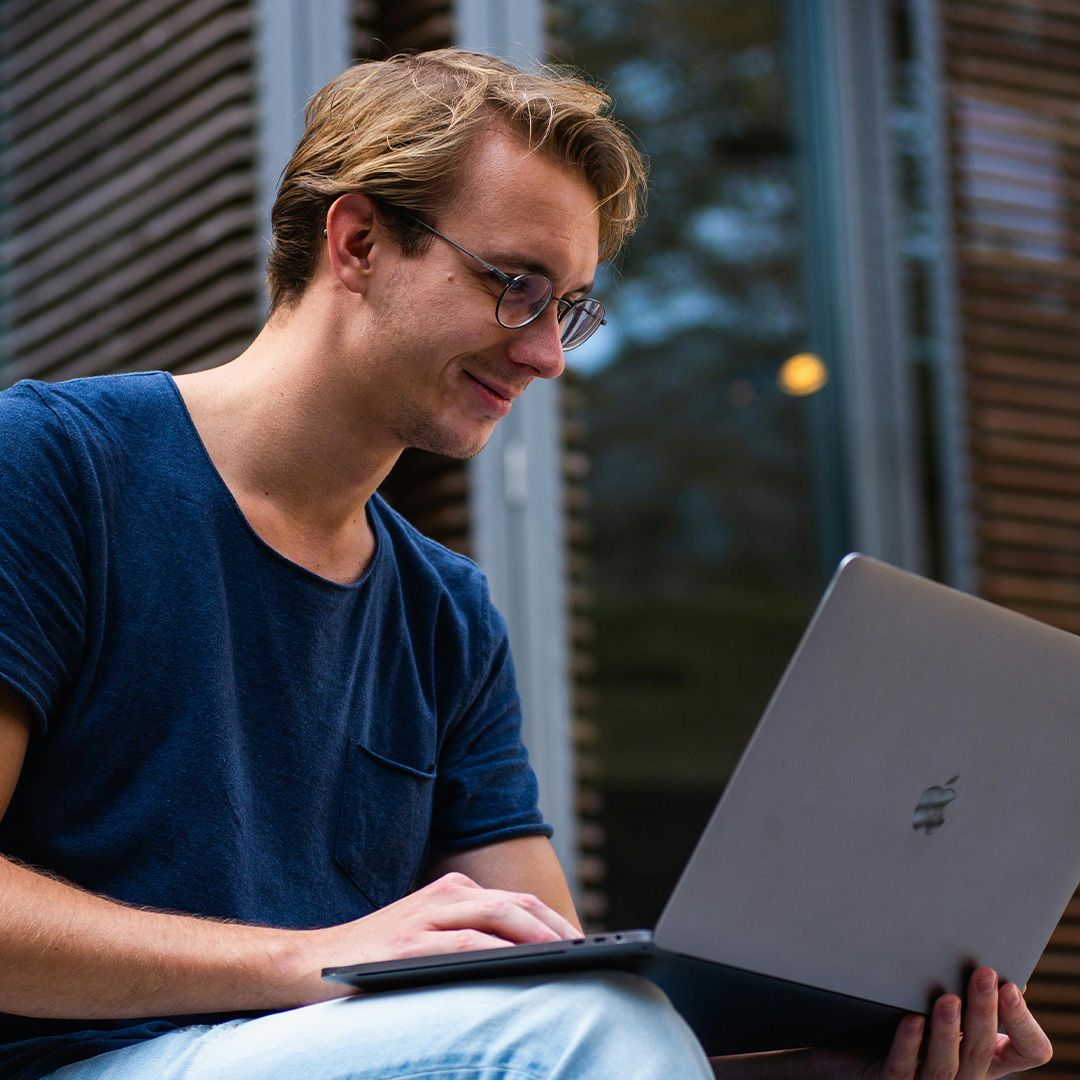 male with glasses sitting with laptop
