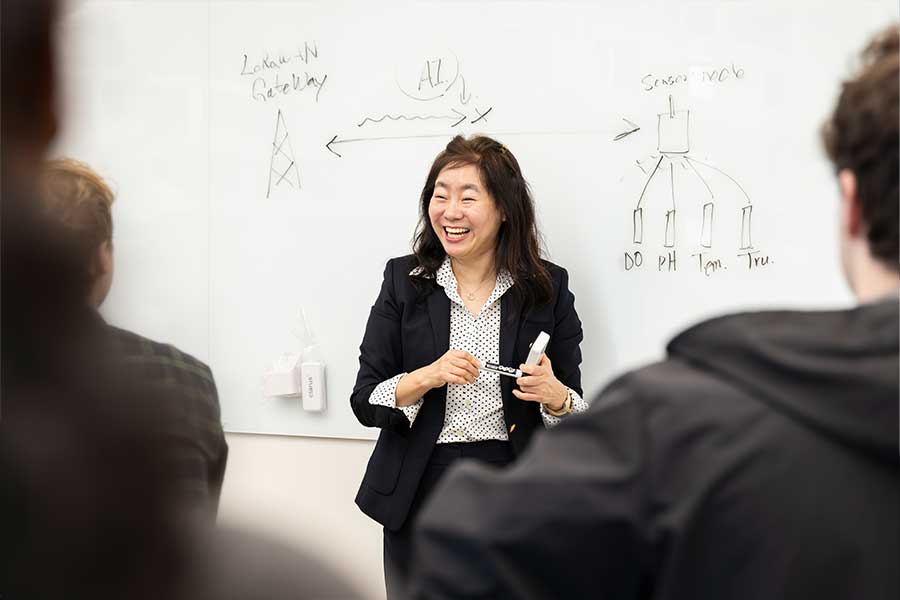 KSU faculty member enthusiastically teaching a class in front of a whiteboard.