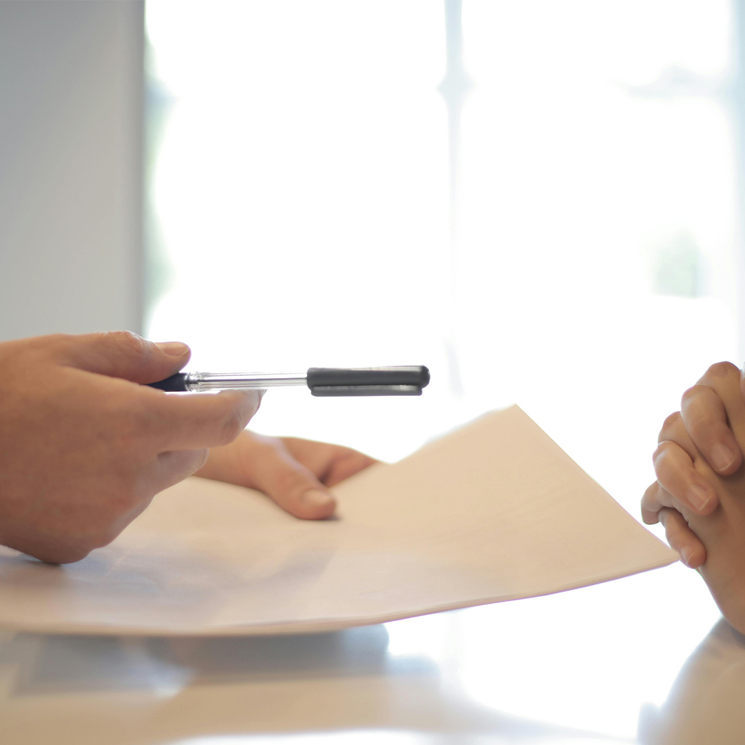 close up of peoples hands in meeting holding pen and paper