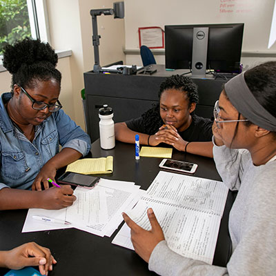 teacher and students talking over books at table