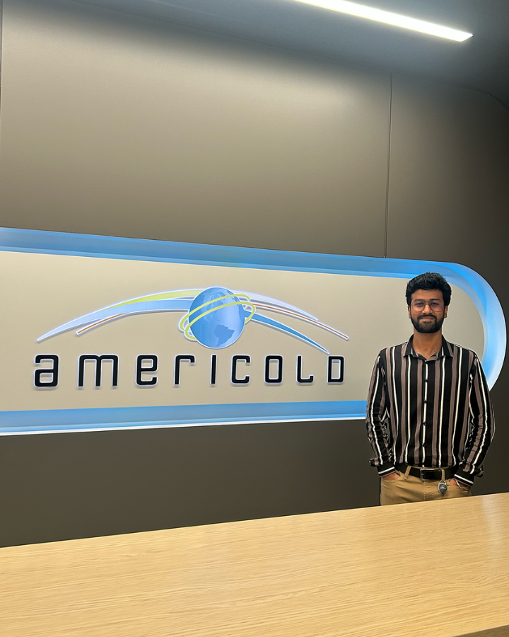 Rohan Bhuin stands in front of the Americold sign.
