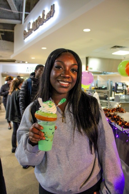 female student holding a green milkshake and smiling