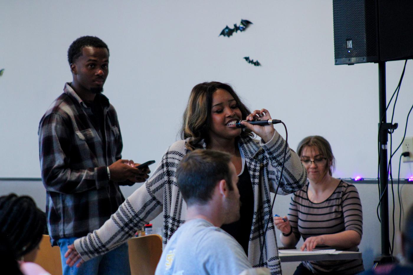 ksu students gathered around a student singing along during karaoke night