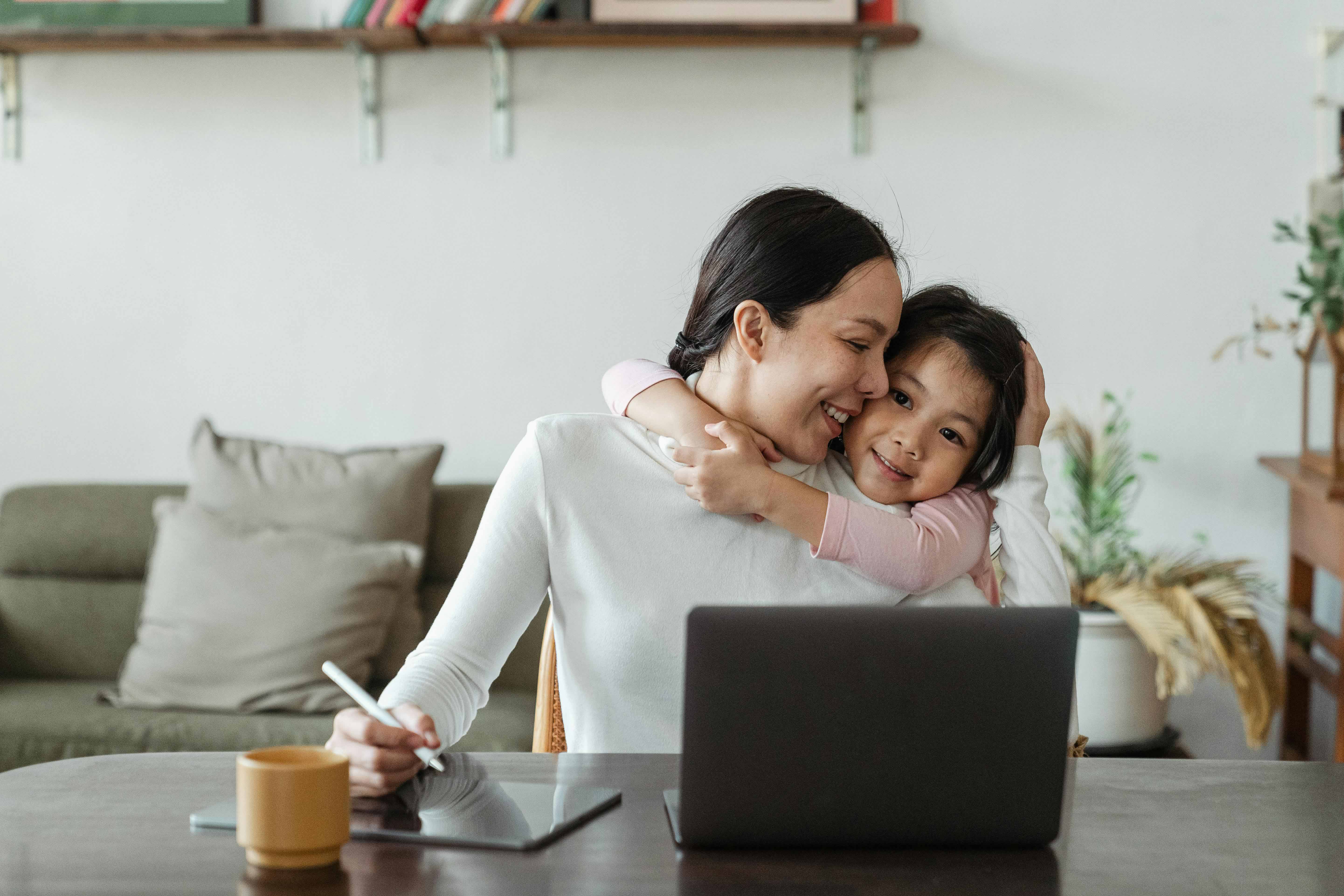 working mom at computer with daughter smiling next to her