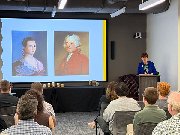 A faculty speaker at a podium speaking to event participants