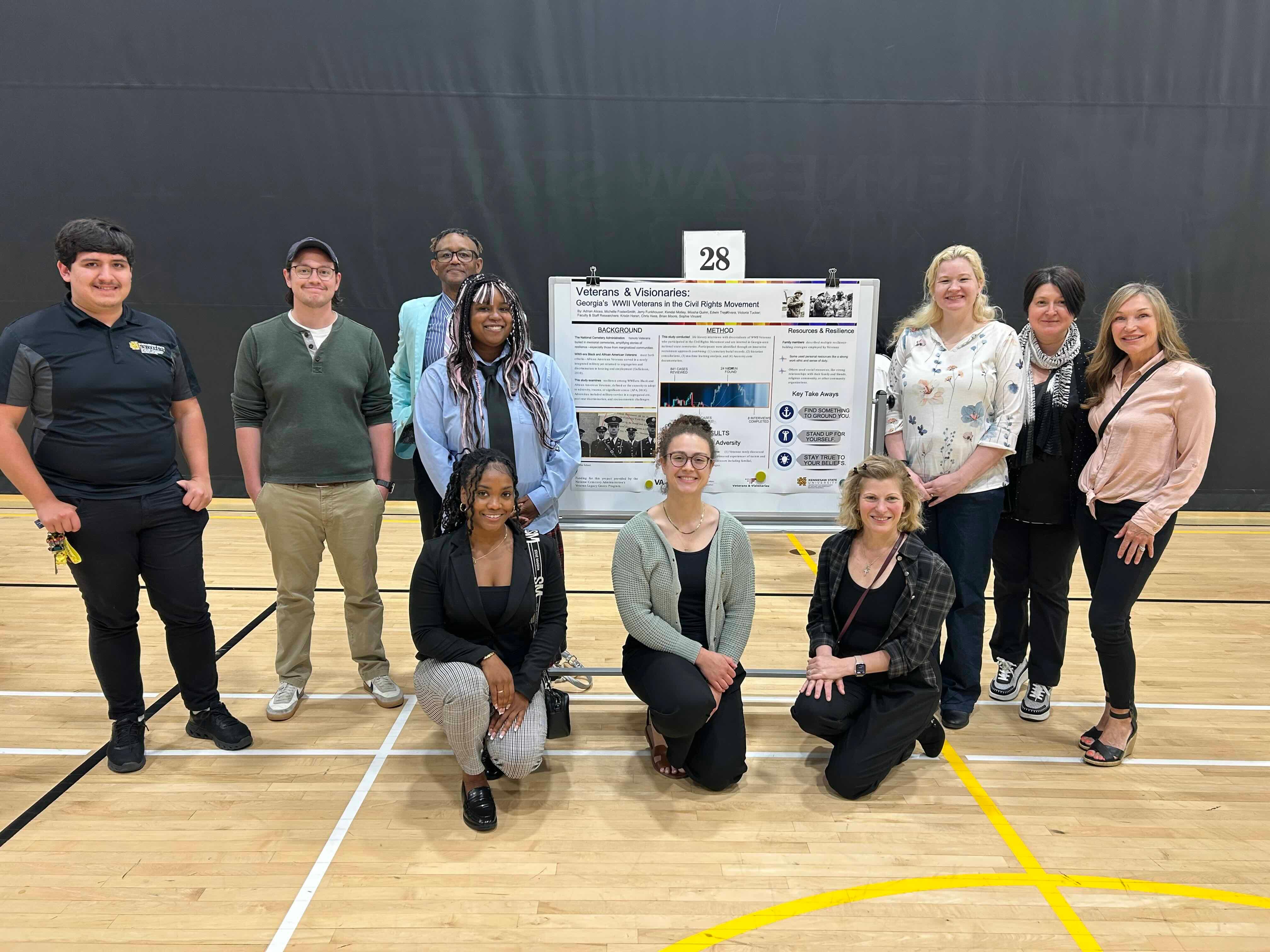 Veterans & Visionaries – Symposium / A group of students pose for a photo with their research poster.