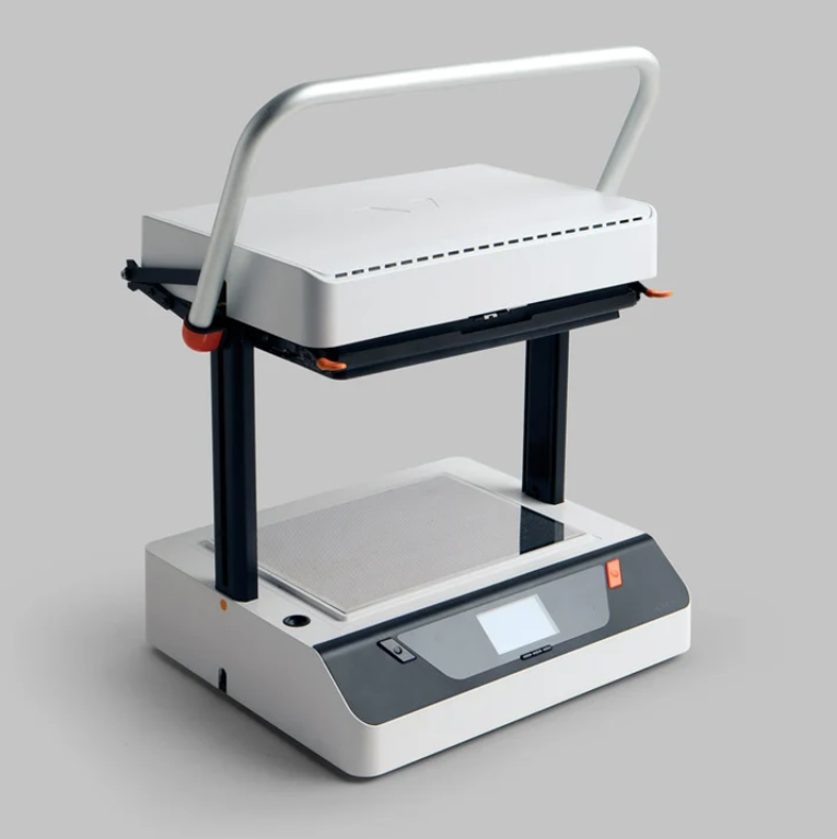Compact tabletop press machine with a raised white upper platen, curved handle, lower platform, and front control panel.