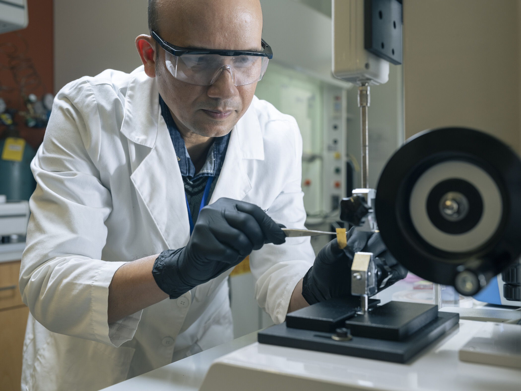 person in research laboratory holds material with pliers