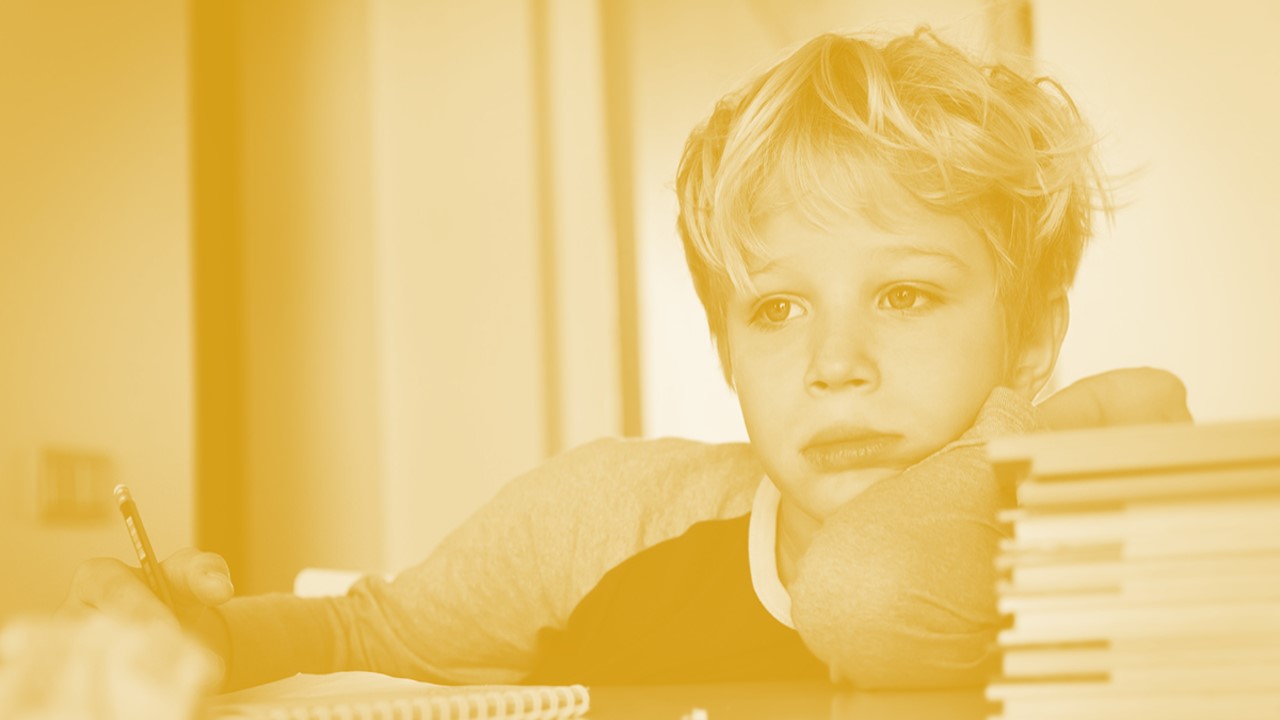 child leaning on table with head positioned on arm