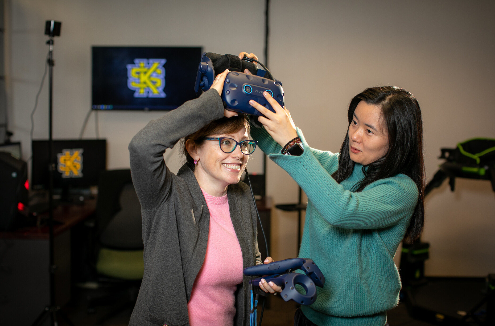 researcher placing virtual reality headset on student.