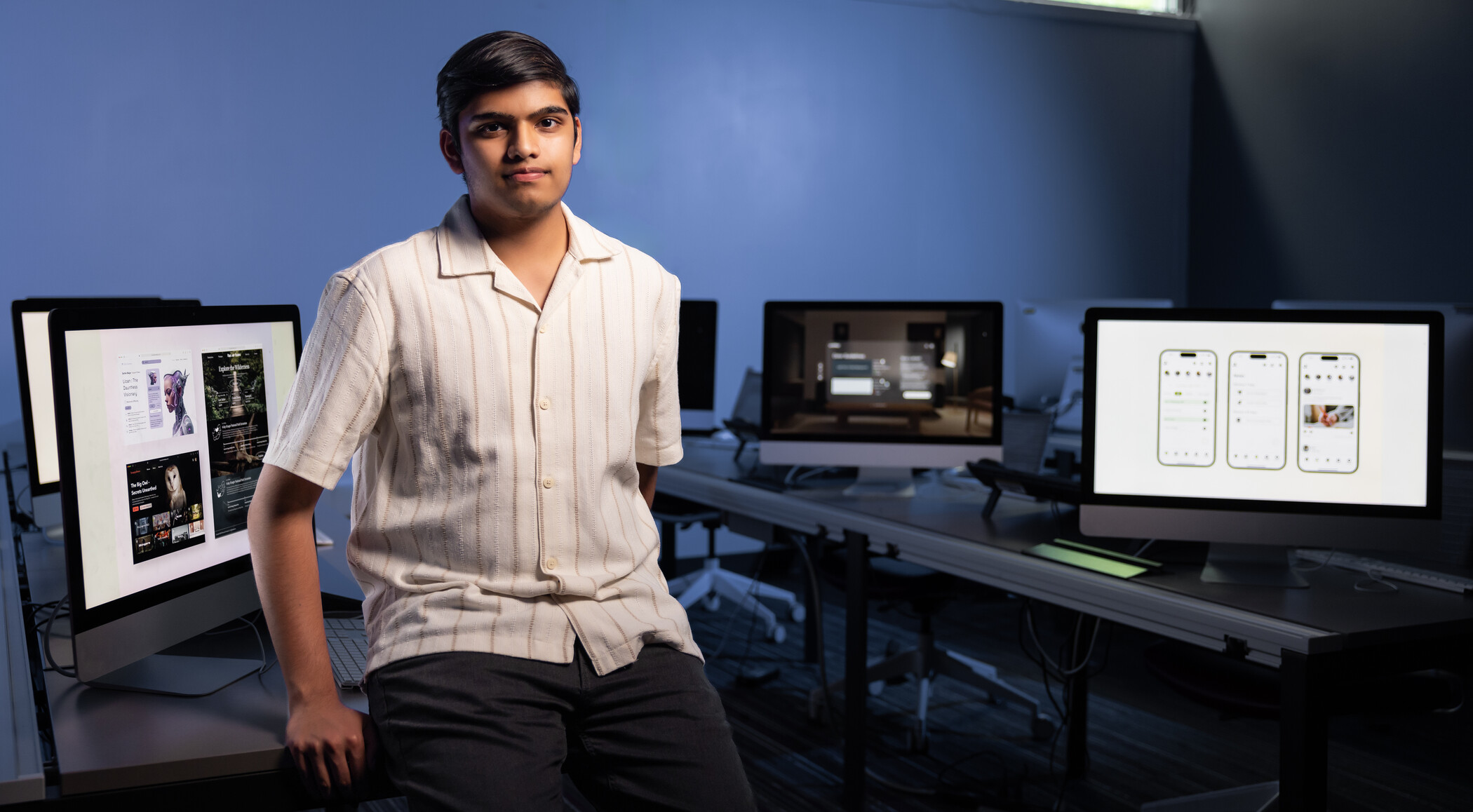 researcher leaning on table in front of series of computer monitors showing user design.