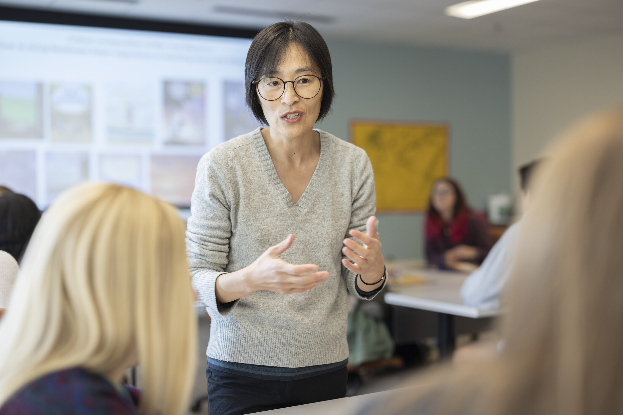 researcher standing in foreground talking with two people.