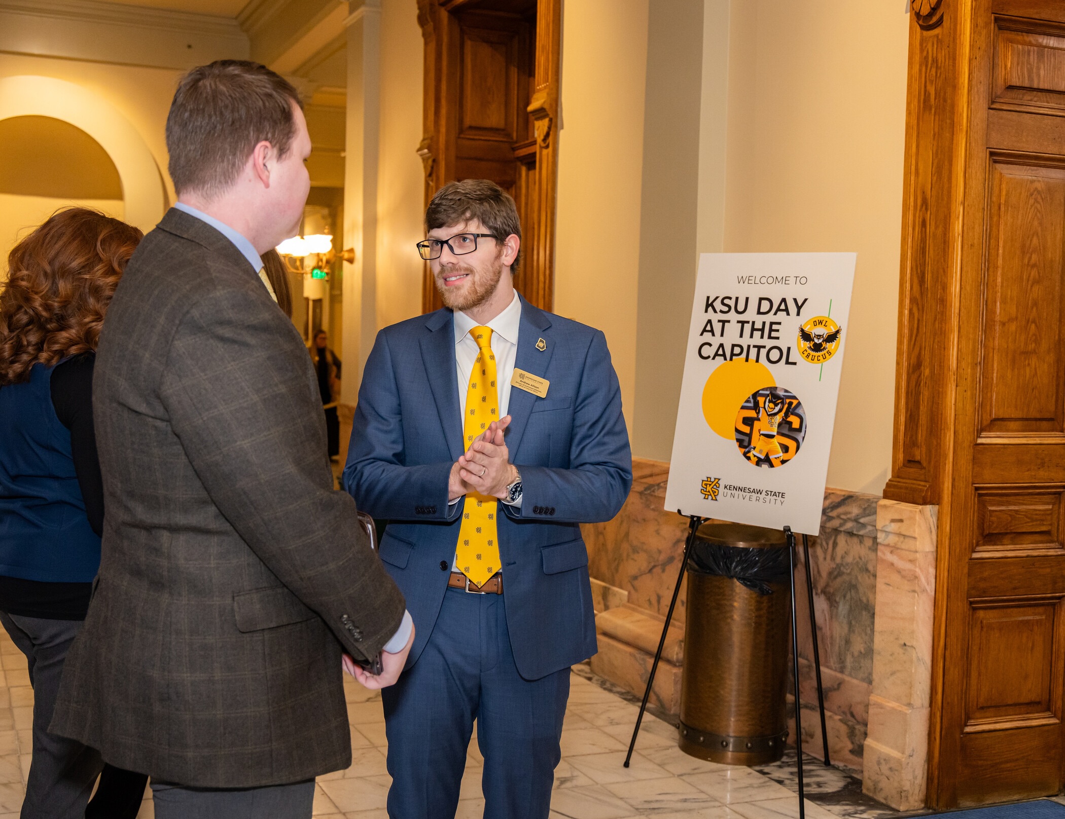 two people in a hallway at the Georgia Capitol in front of a sign reading, "Welcome to KSU Day at the Capitol."