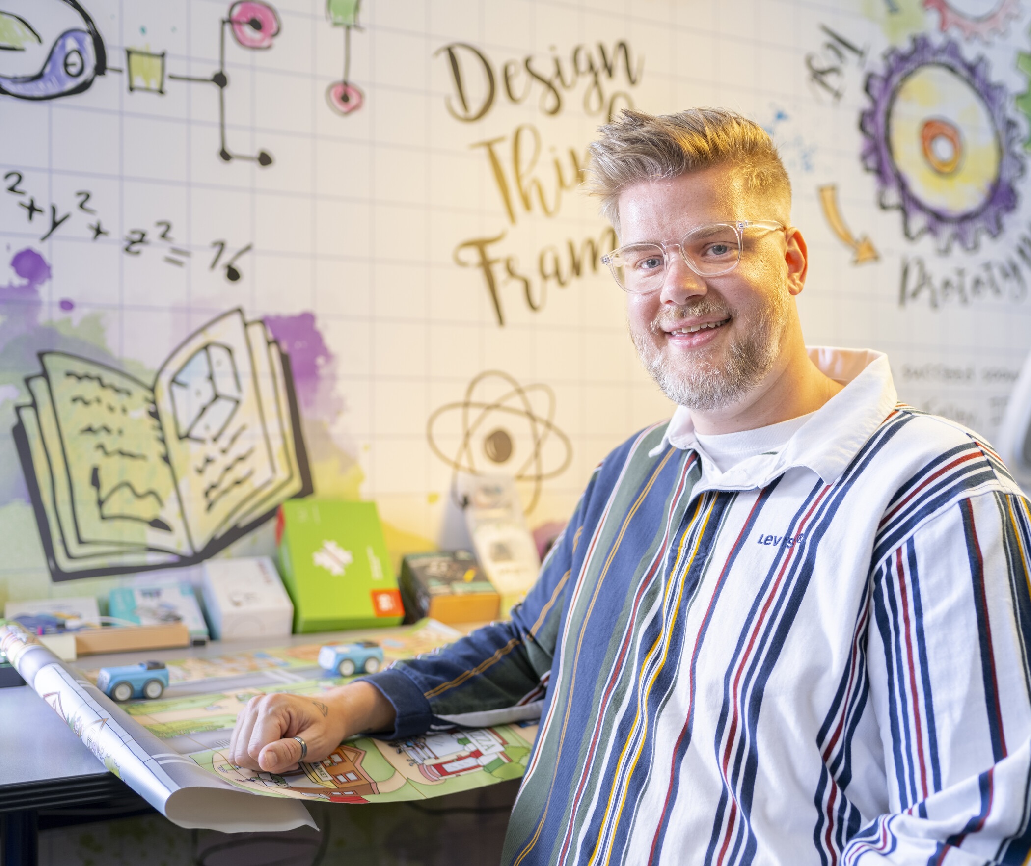 researcher sitting at desk surrounded by STEM-focused iconography.