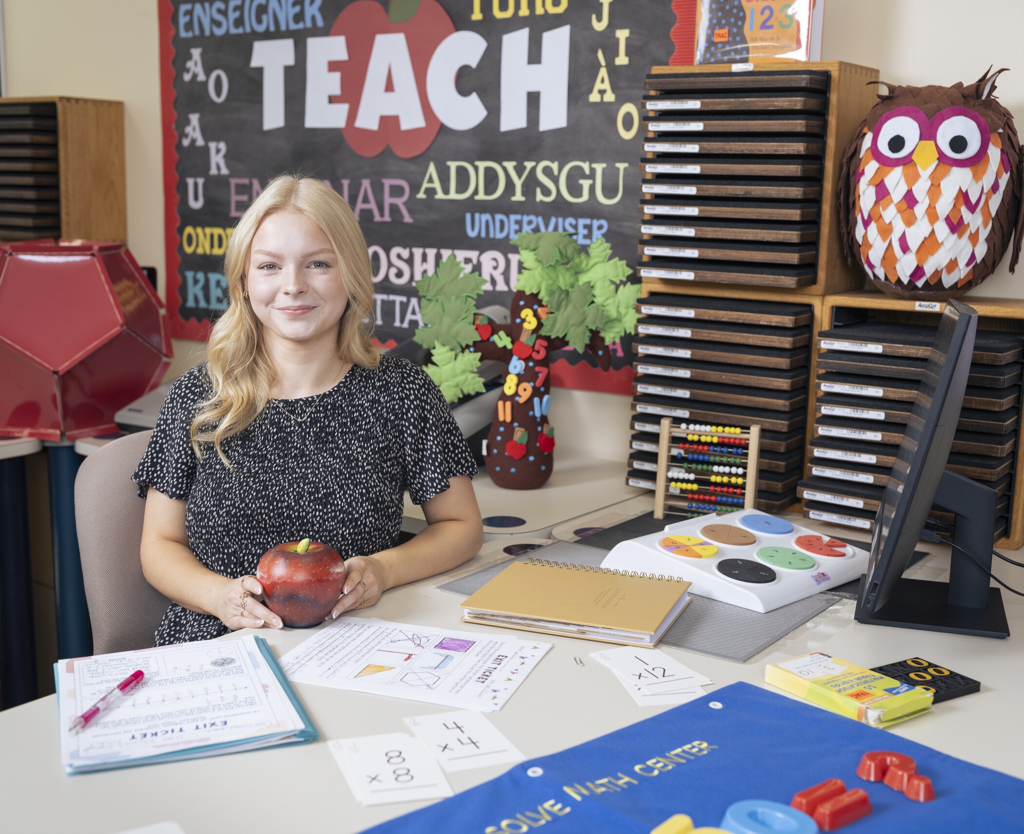 researcher sitting at desk holding paper mache apple.