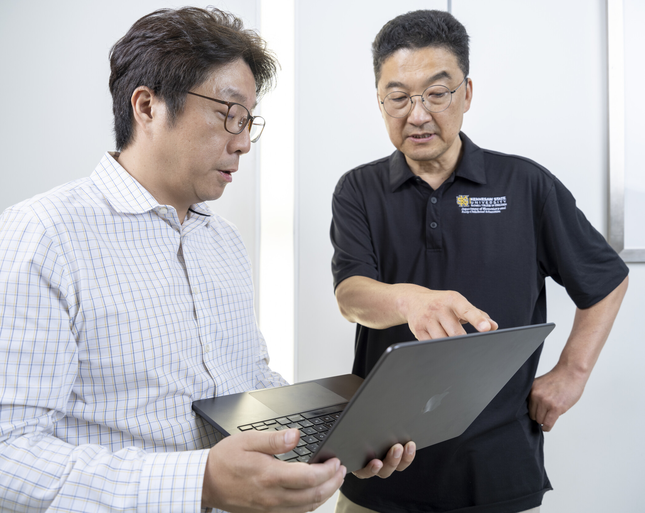 two researchers gesturing at laptop.