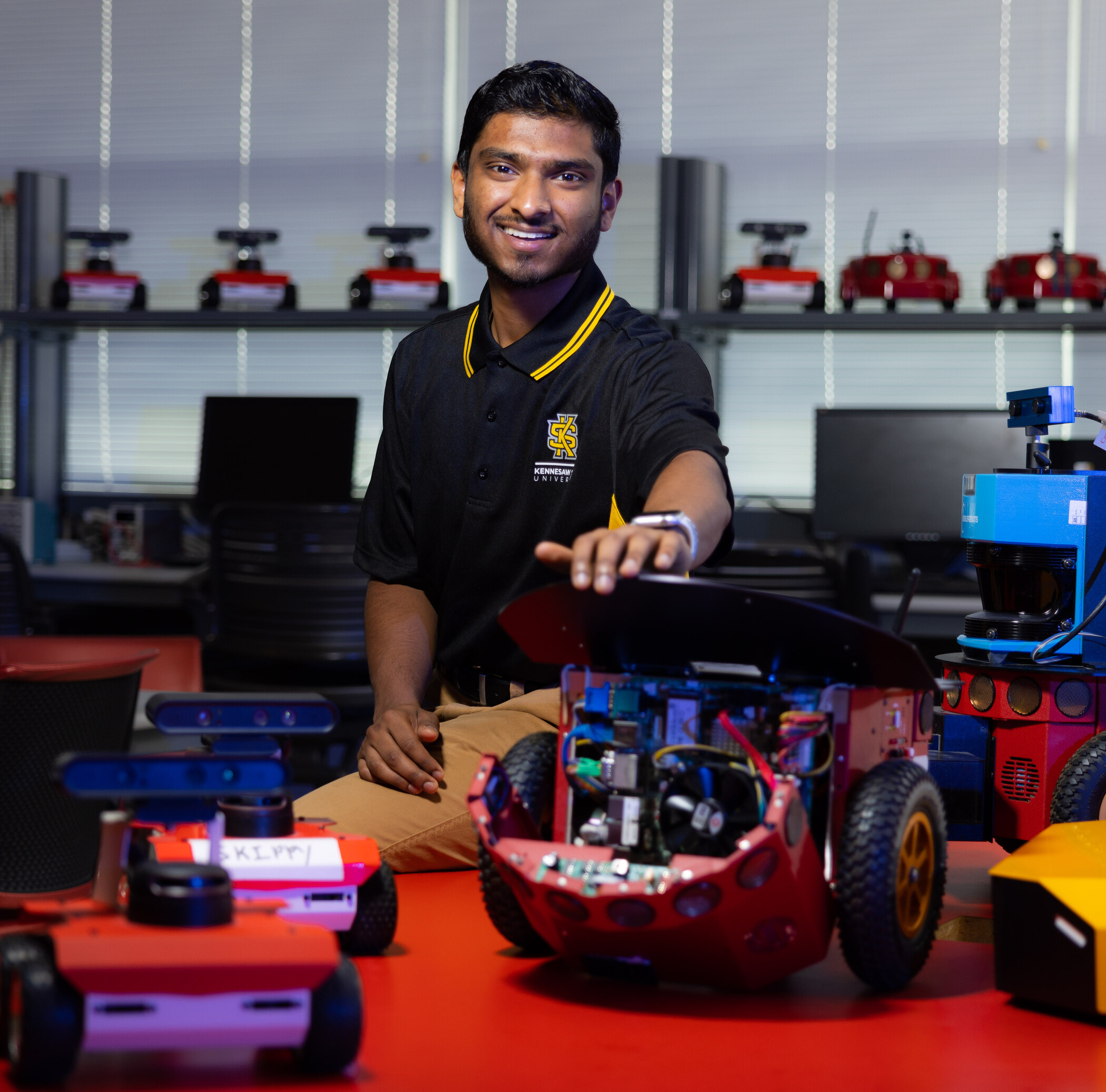 researcher sitting next to robot outfitted with sensors.