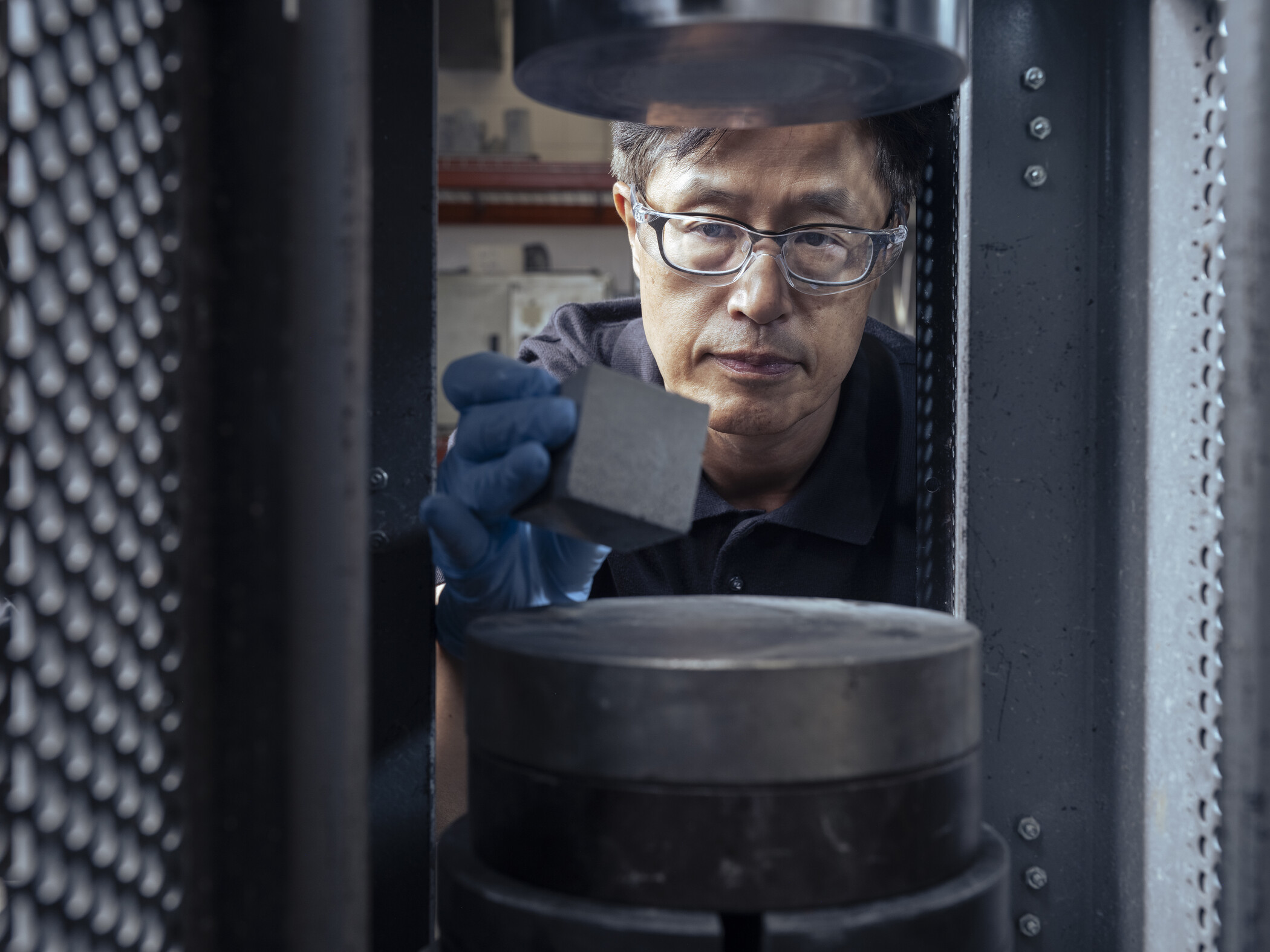 researcher holding material in front of machine.