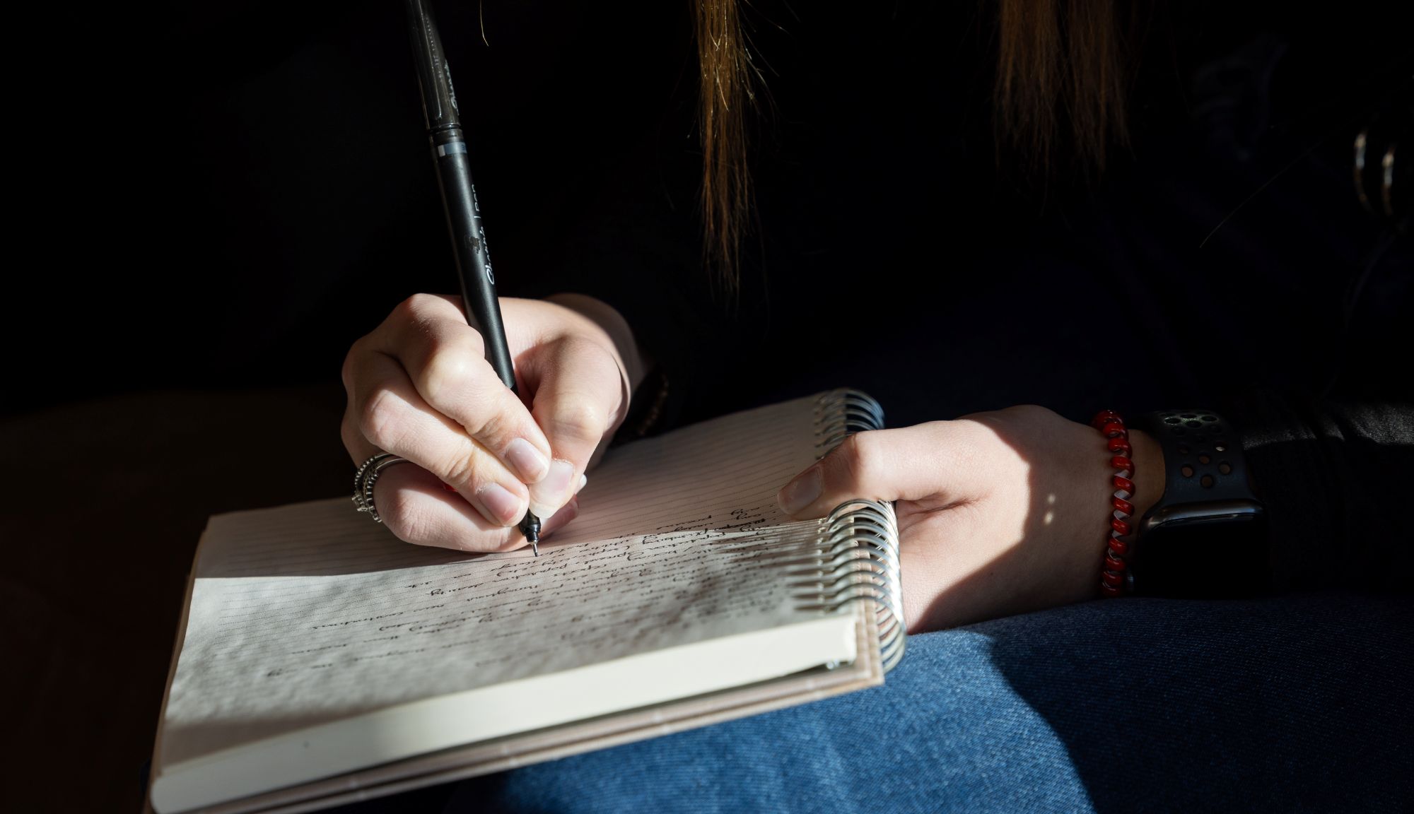 hands holding pen writing in journal