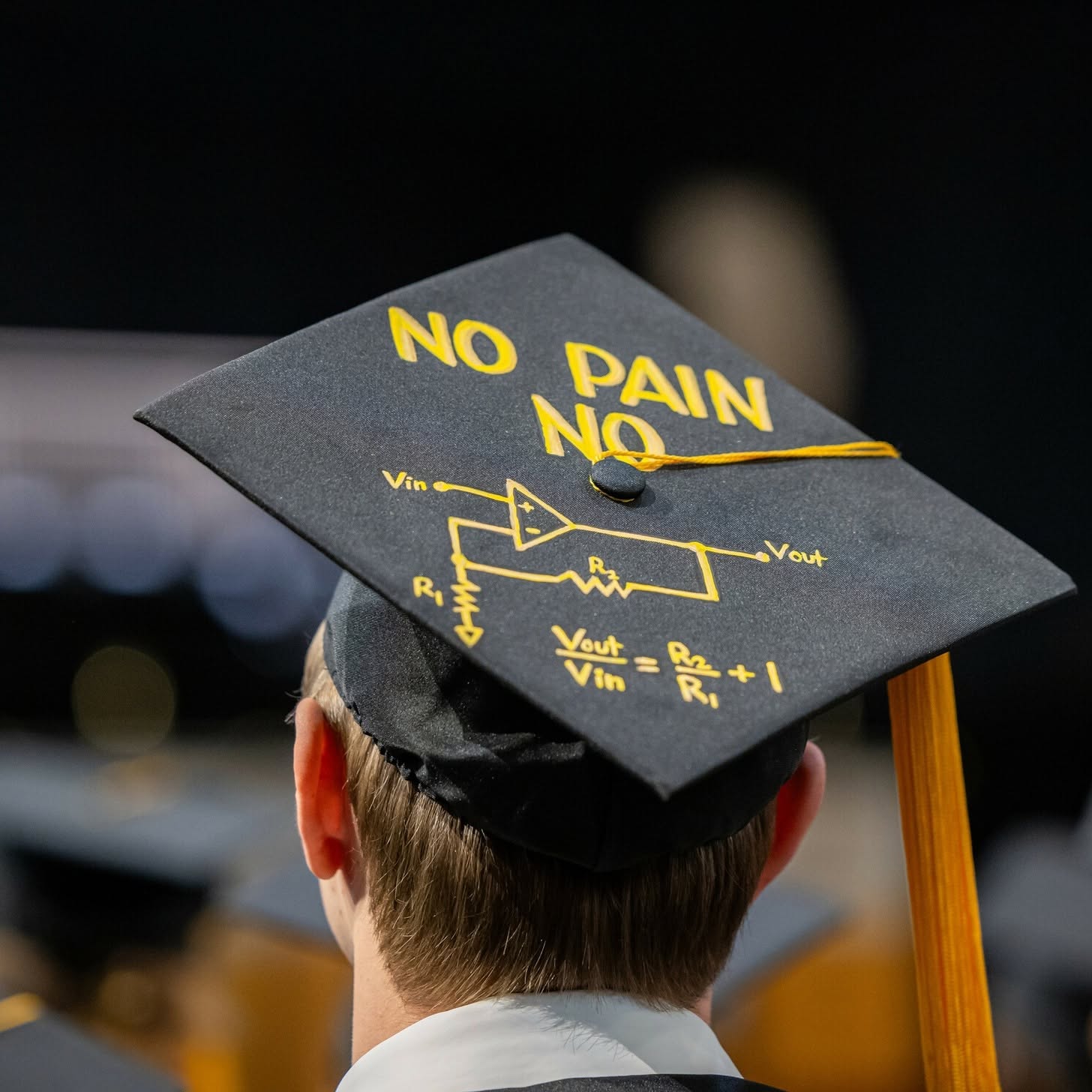 A black graduation cap with yellow lettering that says "NO PAIN NO," featuring a circuit diagram and an equation linking input and output.