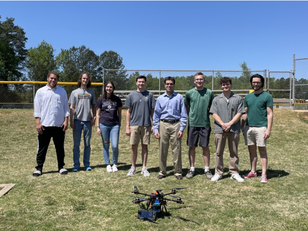 Faculty mentor and students taking picture with their invention