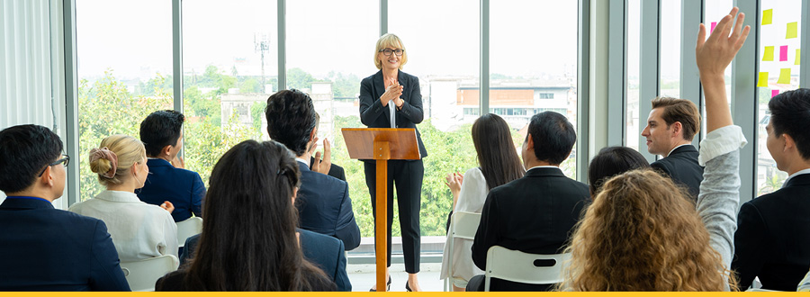 A woman presents to an audience, engaging them with her speech and visual aids.